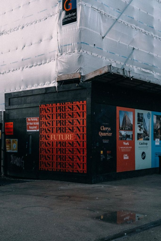 Building exterior with bold Past Present signage at an urban construction site.